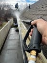 Close-up of gutter cleaning with pressure washer, outdoors, during the day.